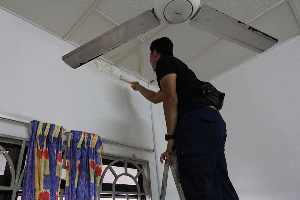 Husin painting the wall of the bedroom